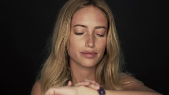 Woman nervously running hands through hair and checking time on wristwatch