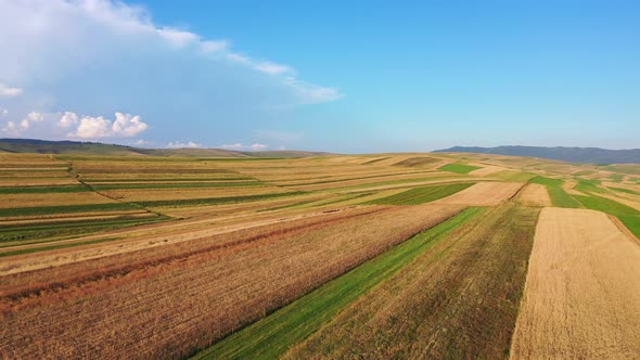 Drone footage of flying over vast farming fields of a hilly rural countryside