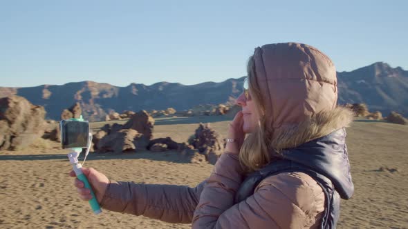 Pretty Girl Takes Selfies Against a Martian Landscape of Volcanic Lava in Cold and Windy Weather and