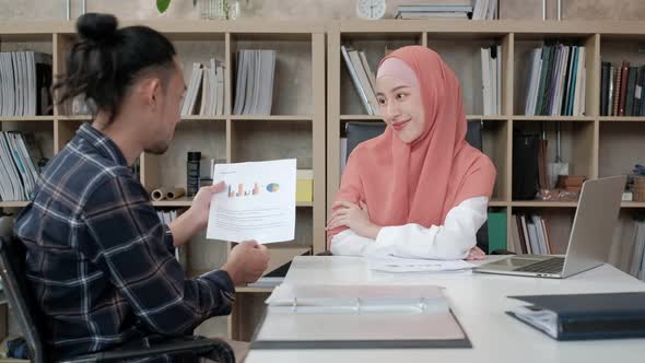 A male worker presents business ideas to a beautiful Islamic boss.