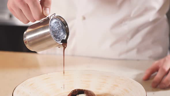 Close-up Hands of Male Chef Poured Chocolate Sauce the Original Dish of Ice Cream