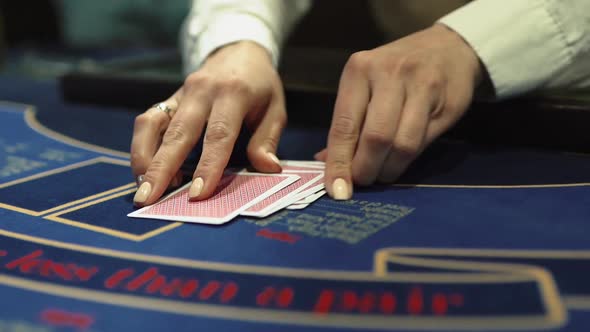Dealer Hands Out Playing Cards on the Gaming Table in the Casino