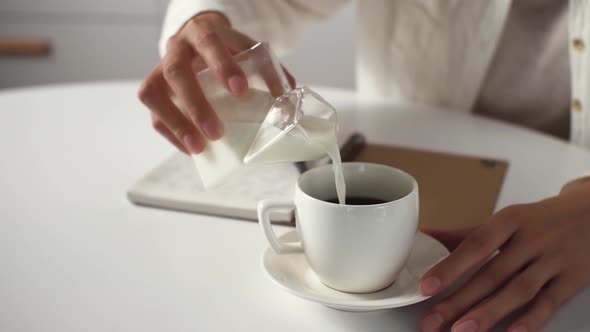 Joyful Relaxed Woman Adds Vegetable Milk To Coffee, Hand Of A White Girl Pours Milk From A Milk