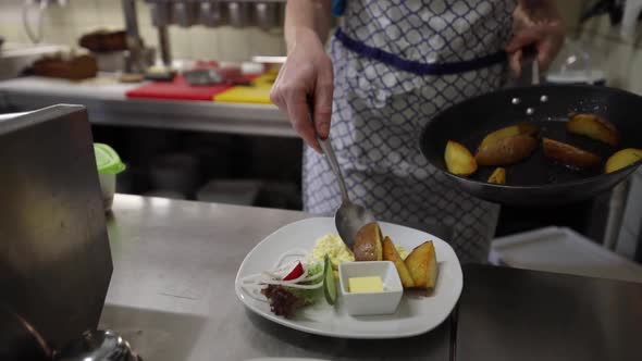 Chef Plating Freshly Cooked Potatoes In The Kitchen - dolly shot, slow motion