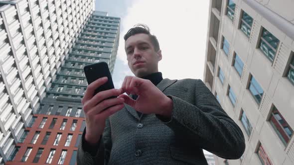 Man Using Business App on Smartphone on City Background. Handsome Young Businessman Communicating on