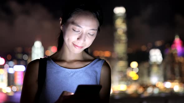 Woman use of mobile phone in city at night 