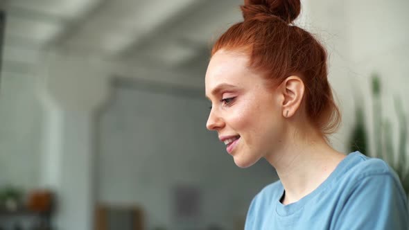 Close-up of Face of Happy Redhead Woman Working on Laptop at the Home Office.