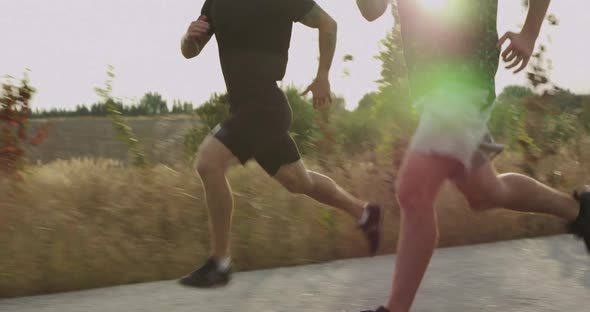 Two Sportsmen Jogging on Asphalt Walkway at Nature on Sunset