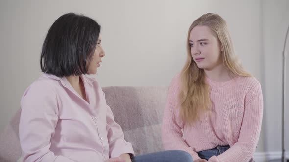 Portrait of Blond Caucasian Girl Sitting on Couch with Mom and Talking. Teenage Daughter Spending