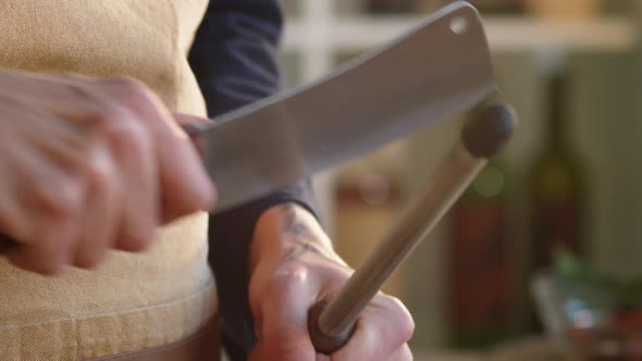 Hands of Male Chef Sharpening Butcher Knife