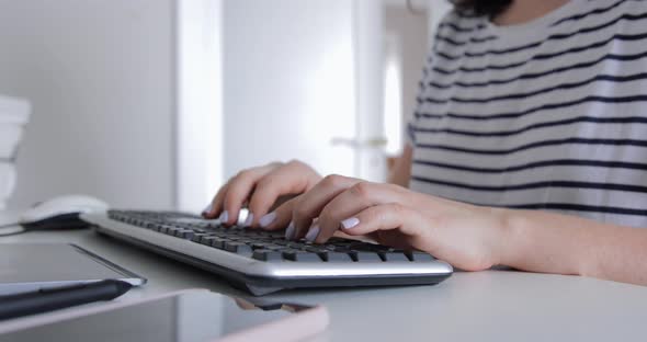 Close up of female freelancer hands as she clicks keyboard and navigates a computer program 