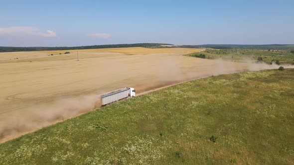 Aerial View of Lorry Cargo Truck Driving on Dirt Road Between Agricultural Wheat Fields