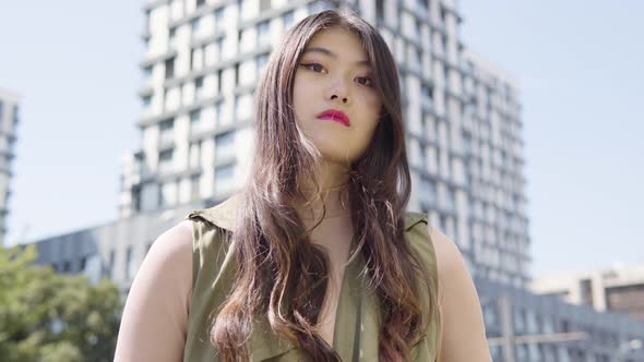 Young Asian Woman Looks Seriously Camera Street Urban Area  Closeup From Below