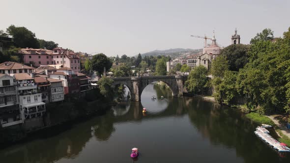 Medieval bridge of Amarante town with cityscape and river water, aerial flying forward view