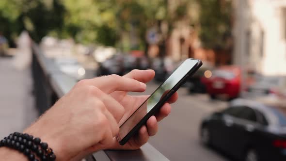 Male Hand Using Smartphone Closeup in the Summer City