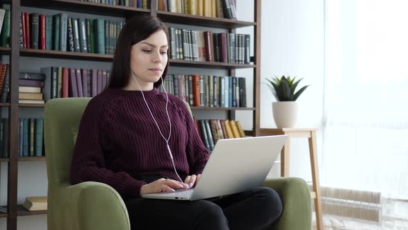 Casual Sitting Woman Listening Music in Headphones and Enjoying