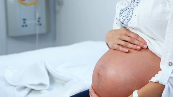 Pregnant woman touching her belly in ward
