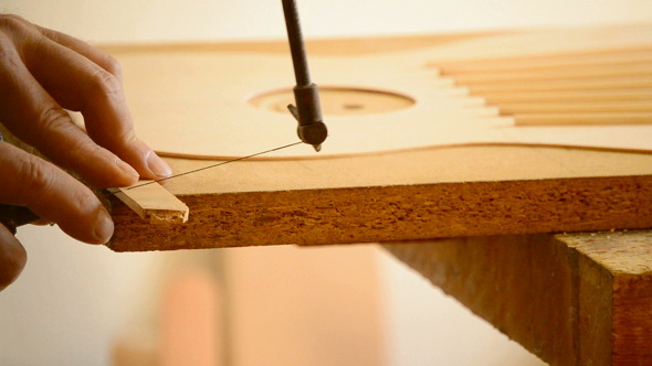 Luthier Cutting a Rod With a Hacksaw