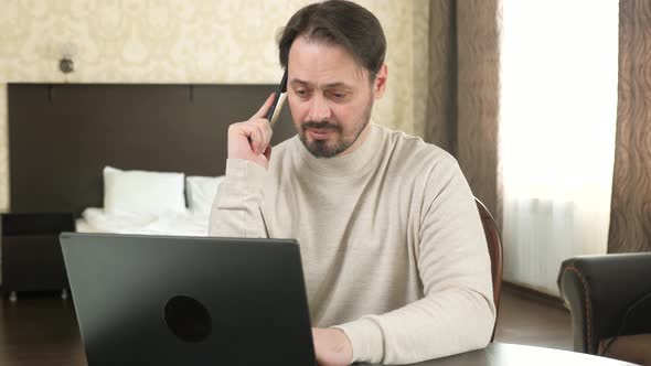 Freelance Worker Working with Modern Laptop and Cell Phone in Room