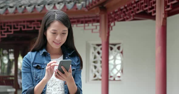 Woman use of mobile phone in Chinese garden