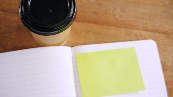 Coffee with organizer and sticky note on wooden table