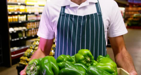 Male staff holding fresh capsicum in wicker basket