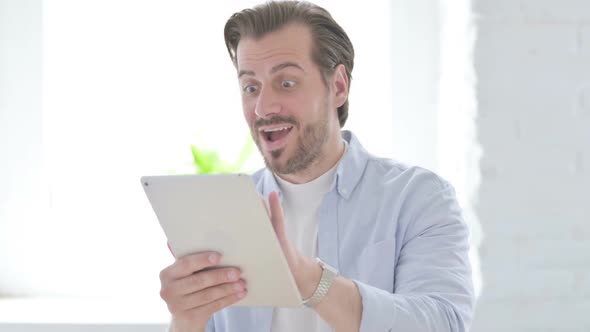 Young Man Celebrating on Tablet in Office