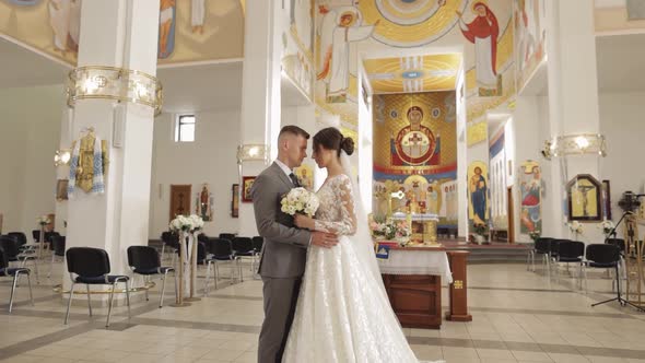 Lovely Family Newlyweds Couple Bride Embracing Groom in an Old Church Wedding Ceremony Matrimony