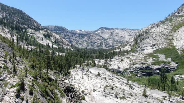 A slow pan 4K aerial drone shot moves down a rocky canyon in the California wilderness to reveal cli