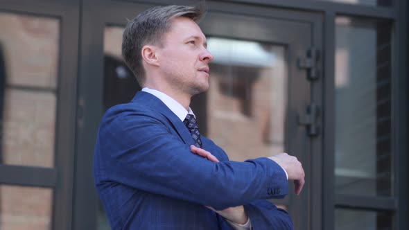 Pensive Businessman Coming and Standing in front of Office