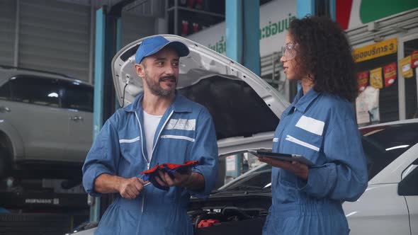 Team of mechanic with man and woman holding tablet computer in uniform talking and discussion.