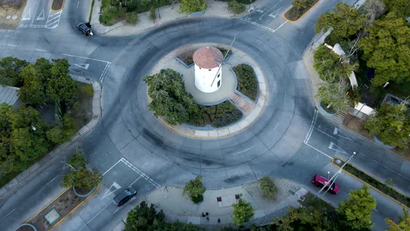 Aerial rising over Leonidas Montes windmill tower in roundabout with cars commuting surrounded by tr