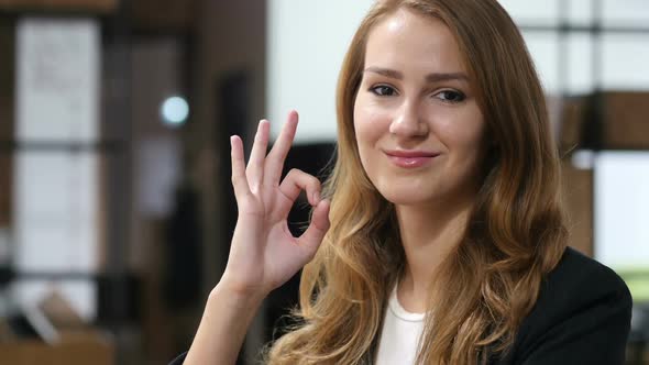 Okay, Sign of Satisfaction by  Smiling Beautiful Girl Sitting Indoor