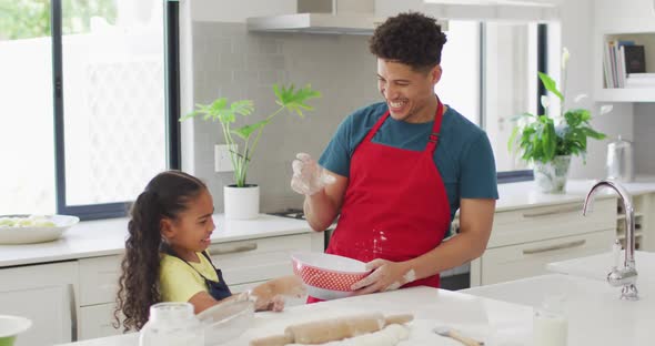 Happy biracial father and daughter baking together in kitchen