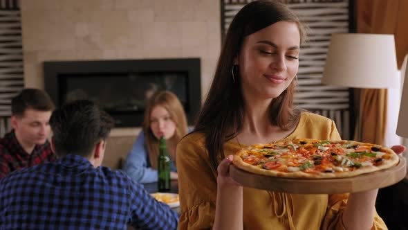 Portrait of a Cute Girl with a Pizza in Her Hands in a Crowded Pizzeria