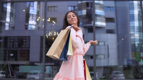 Young Girl in a Dress After Shopping Posing with Packages in Hands