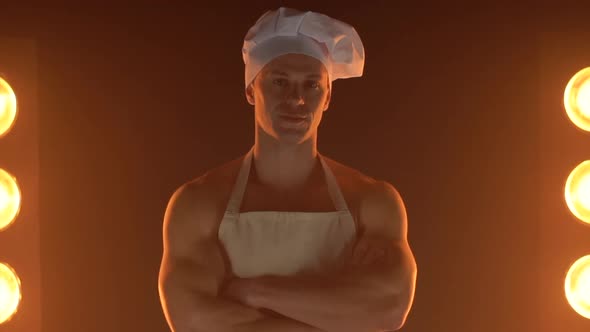 Portrait of Muscular Chef Wearing White Apron and Chef Hat on Smoky Background