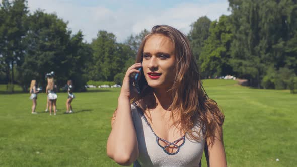 Happy Smiling Cheerleader Woman Talking By Mobile Phone During Break Outdoors