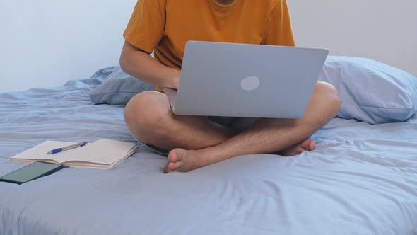 Man Working With A Laptop On The Bed