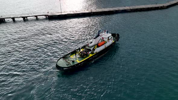 Ship tug sails out of port aerial view