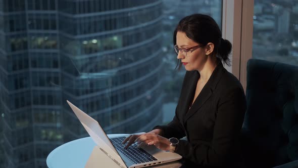 Portrait of a Young Woman Working in an Office Near a Large Window. Modern Business Woman Working on
