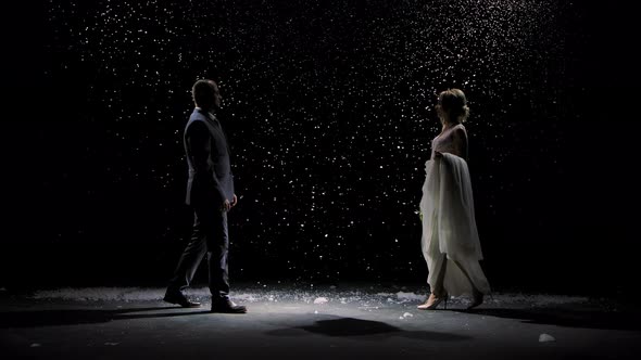 Happy Newlywed Couple Approach Each Other Against the Background of Falling Snow. A Man in a Suit