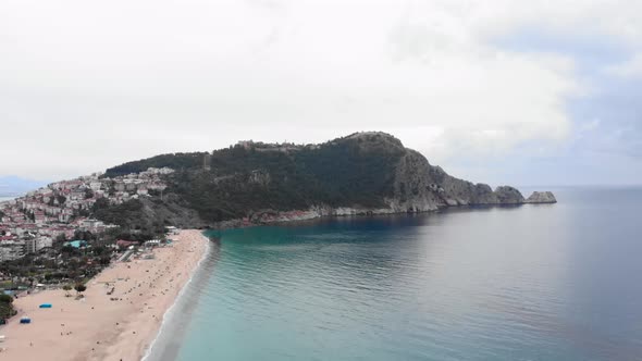 Aerial view of golden beach with clear blue sea water, remains of the fortress in Alanya, Turkey