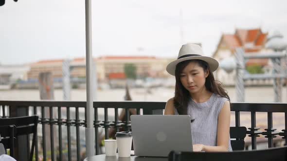 Young Asian woman using laptop working at a cafe shop.