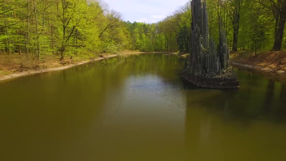 A lake within the forest park, a miniature building in the pond and a perfect curb foot bridge that