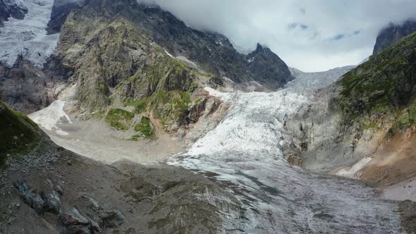 Aerial View of a Mountain Glacier on a Summer Day Against the Backdrop of a Cloudy Sky