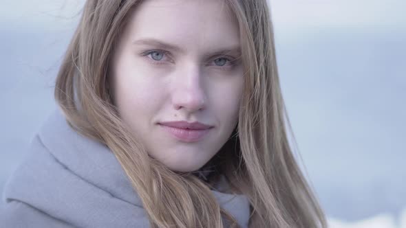 Portrait of Beautiful Young Blond Woman with Long Hair and Blue Eyes Looking in the Camera