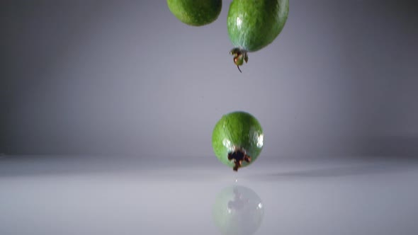 Feijoa fruits falling on water surface. Slow Motion.