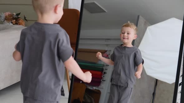 A Little Boy Jumps Near a Mirror in a Photo Studio