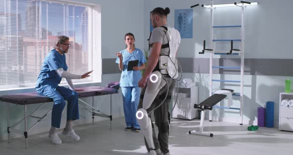 Patient in Exoskeleton Walking Towards Doctors